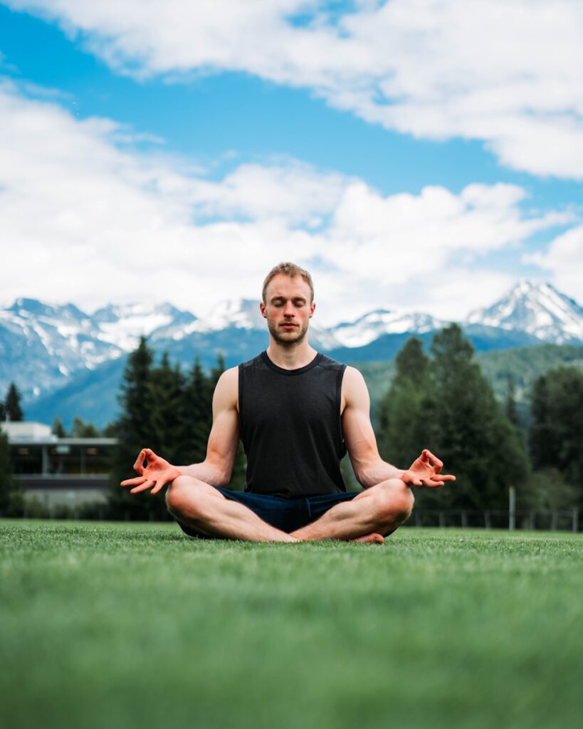 a man sitting in a yoga position in a field
